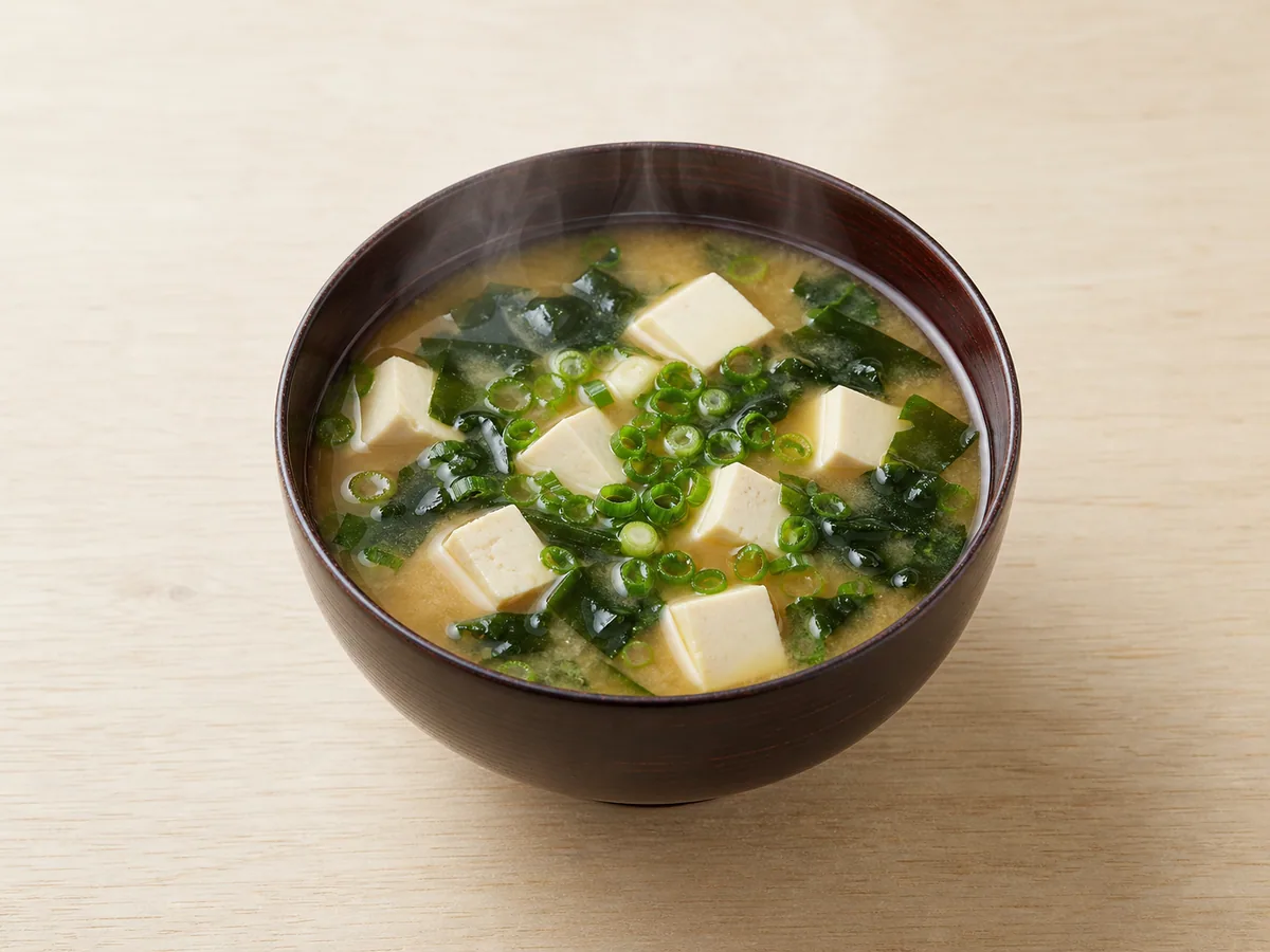 Japanese miso soup with tofu cubes, wakame, and green onion in a lacquer bowl