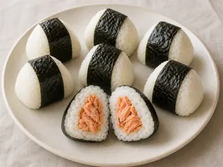 Onigiri japonés de salmón envuelto en nori crujiente sobre un plato de cerámica