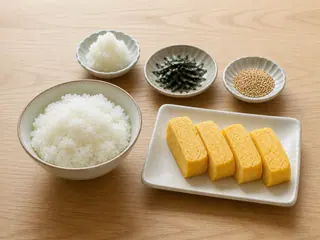 Tamagoyaki japonés en rebanadas junto a arroz al vapor con daikon rallado, nori y ajonjolí