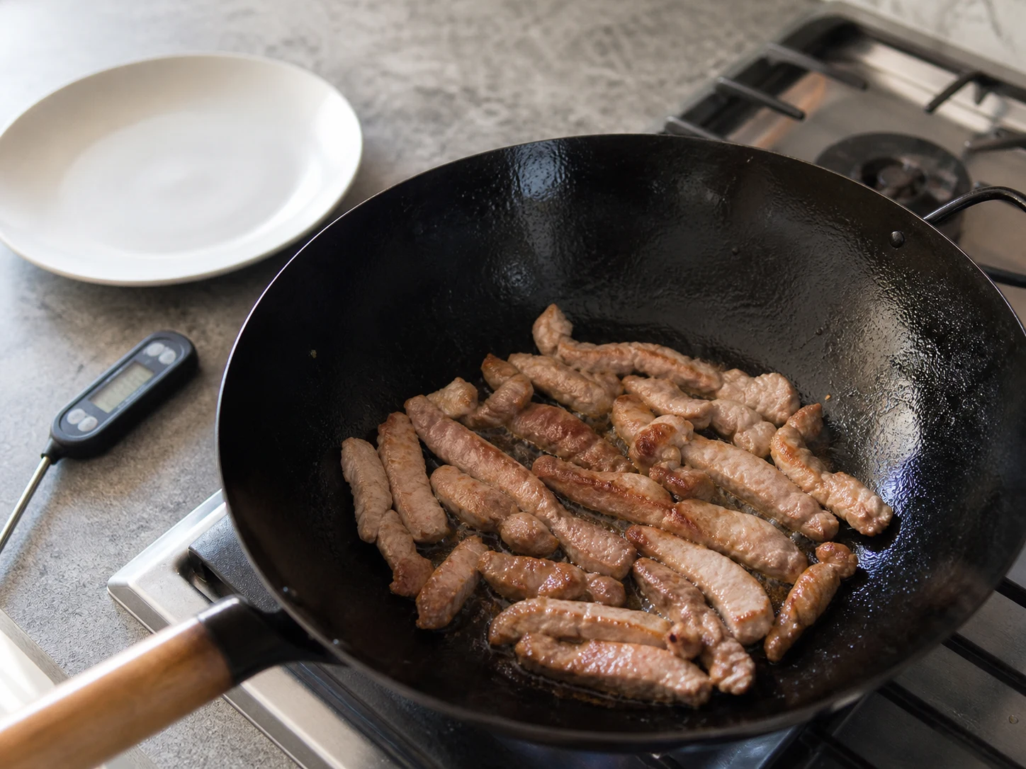 Tiras de cerdo doradas y completamente cocidas reposando en un plato limpio antes de saltear los vegetales