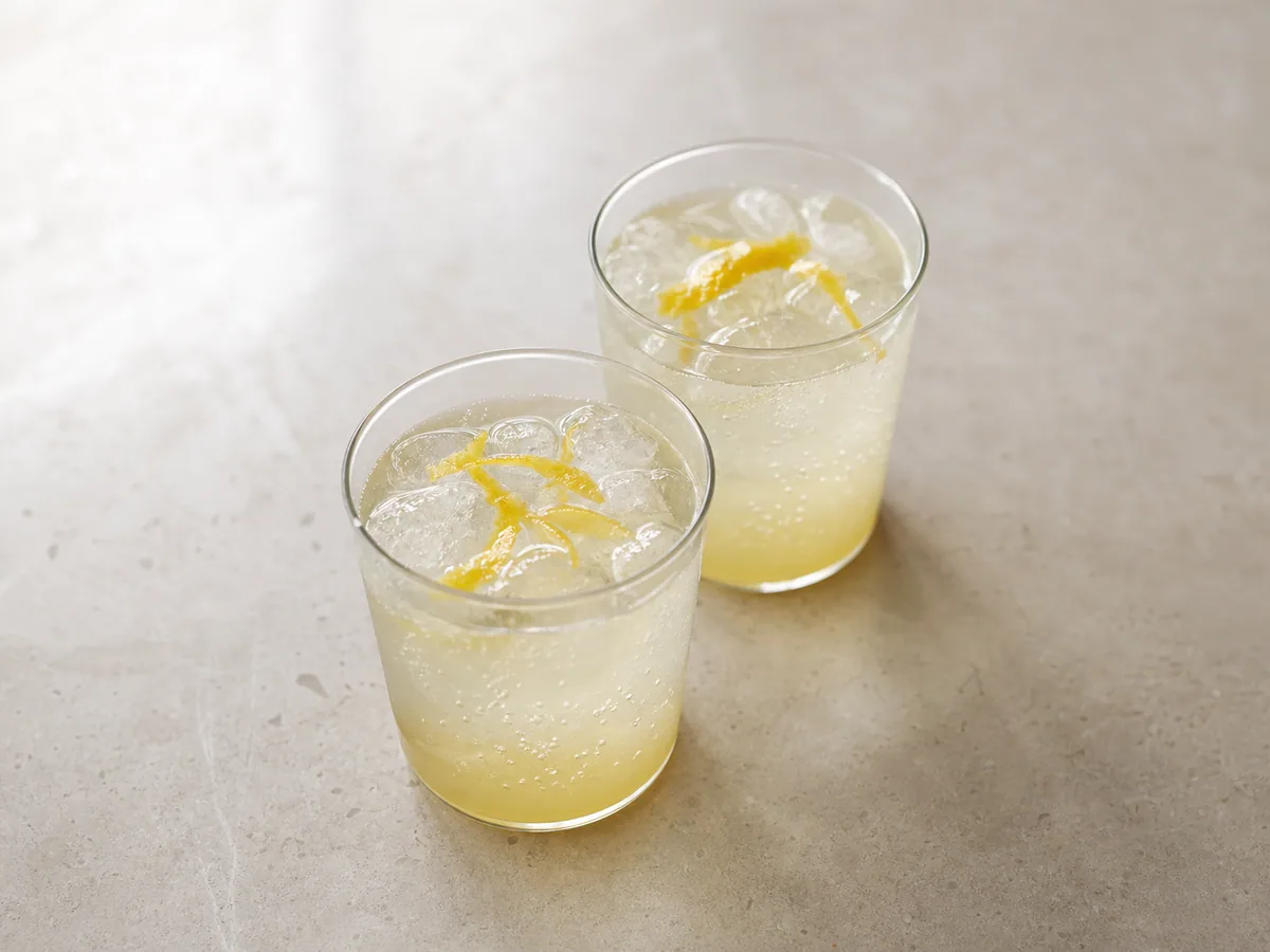 Soda japonesa de yuzu e mel depois de adicionar água com gás sobre o gelo e a base de yuzu e mel, com bolhas finas e espuma controlada antes de acrescentar a casca