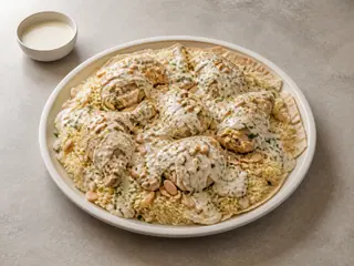 Jordanian chicken mansaf with yogurt-sauced rice, almonds, pine nuts, and parsley