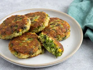 Tortitas doradas de irio keniano con papa y guisantes en un sencillo plato de cerámica