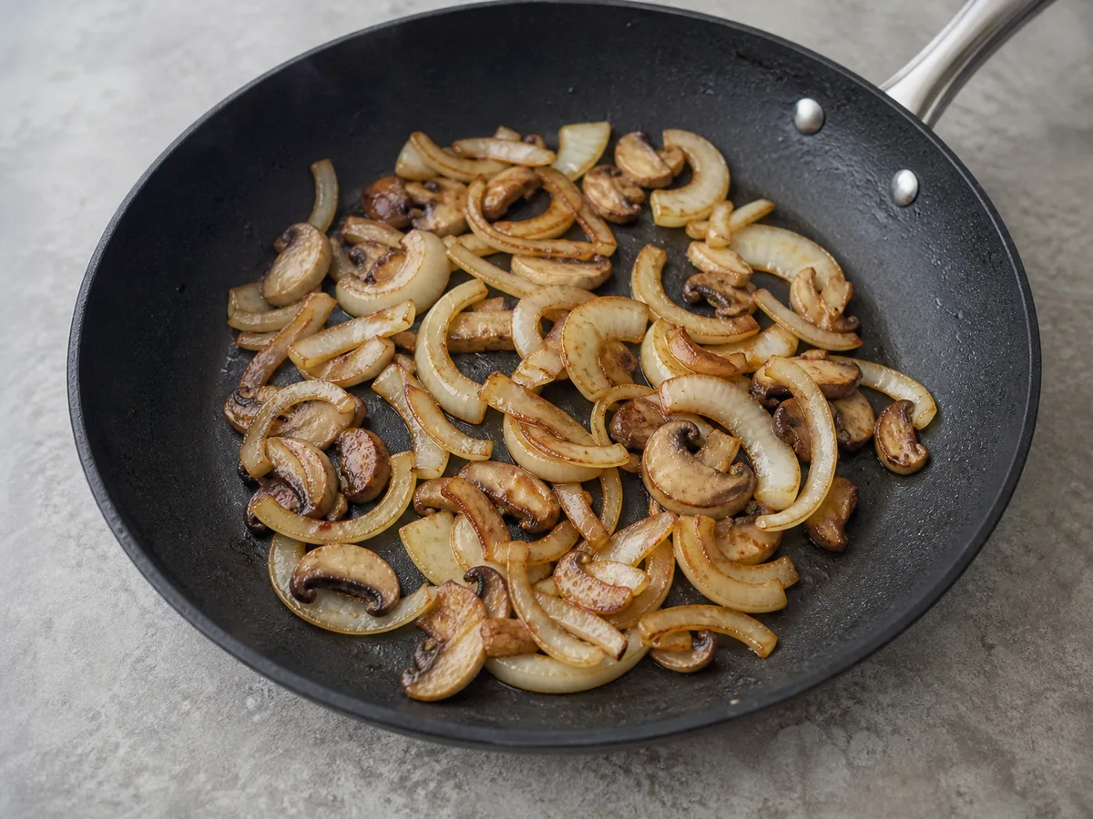 Cebolla, hongos shiitake y partes claras de cebollines ligeramente dorados en una sartén para el bulgogi coreano