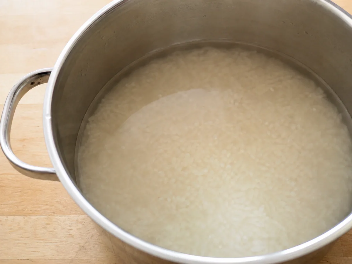 Varios granos de arroz floteo en agua de malta clara tras el calentamiento enzimático