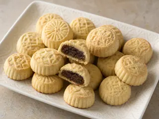 Galletas maamoul libanesas de dátil labradas, con una abierta para mostrar el relleno