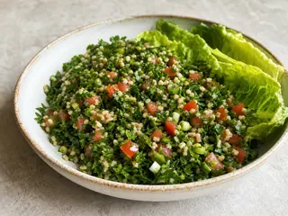 Tabule libanés con abundante perejil en un tazón poco profundo con hojas de lechuga romana