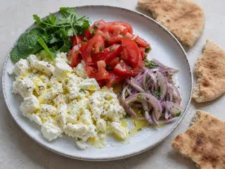 Plato libanés de desayuno con queso shanklish, tomate, hierbas, aceite de oliva y pan pita
