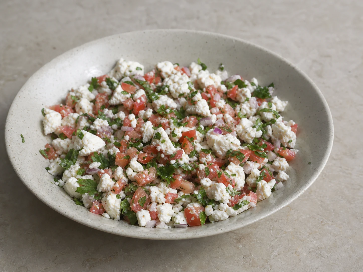 Farelos irregulares de shanklish misturados delicadamente com tomates, cebola, salsinha e hortelã antes de adicionar o azeite