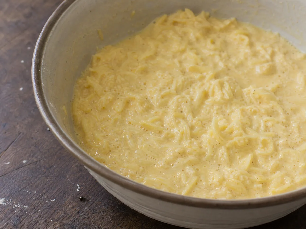 Batatas raladas finamente envolvidas em mistura morna de cebola e leite antes de adicionar os ovos ao kugelis lituano