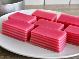 Pink and white slices of Malaysian kuih lapis showing nine steamed layers