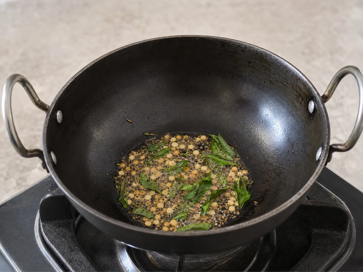 Sementes de mostarda estaladas e chana dal levemente dourado com folhas de curry, gengibre e pimentas verdes