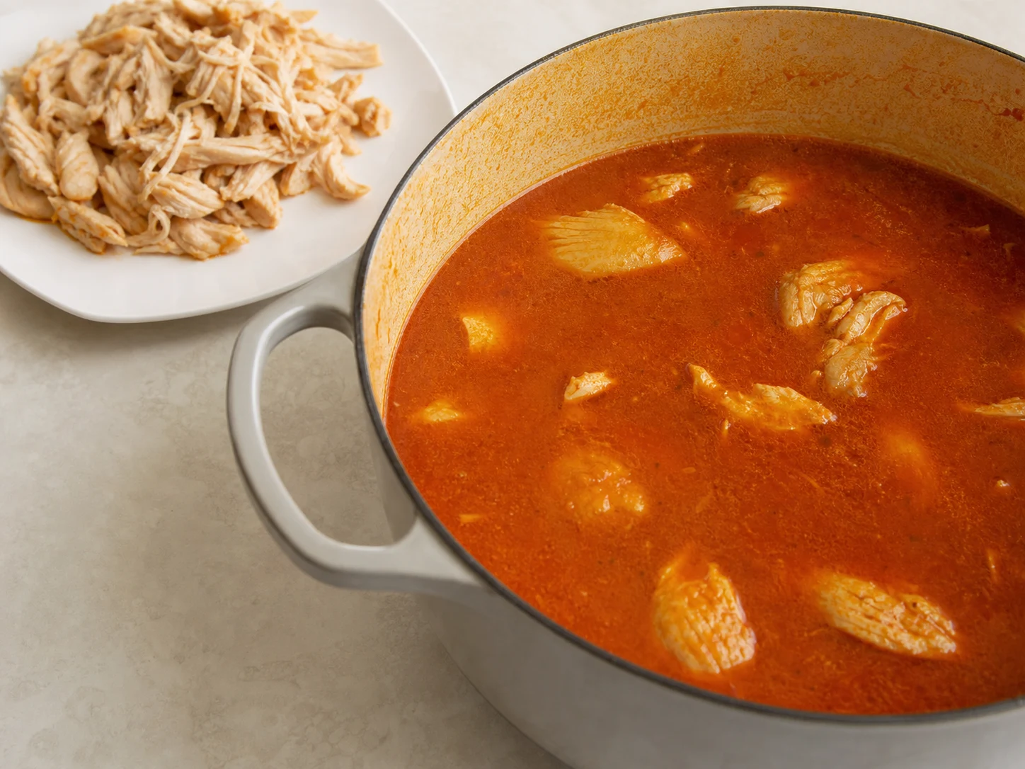 Peito de frango totalmente cozido e desfiado em pedaços macios, em prato limpo, após atingir 74°C/165°F