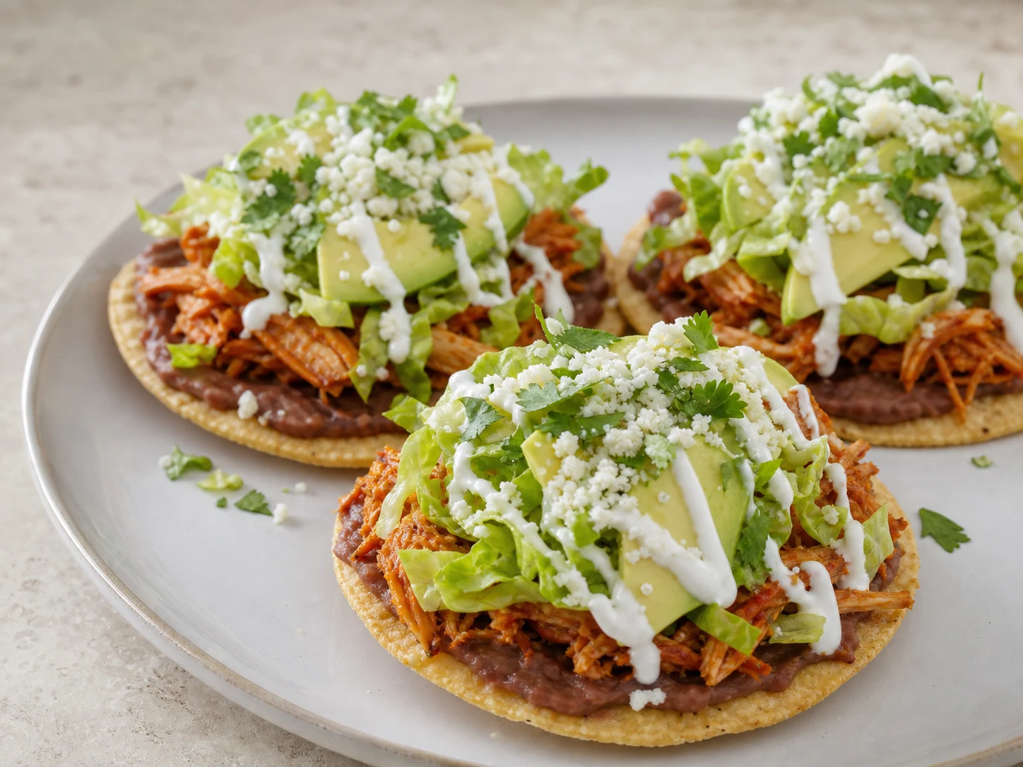 Discos de tostada de milho com feijão-preto e tinga de frango, antes das coberturas frescas