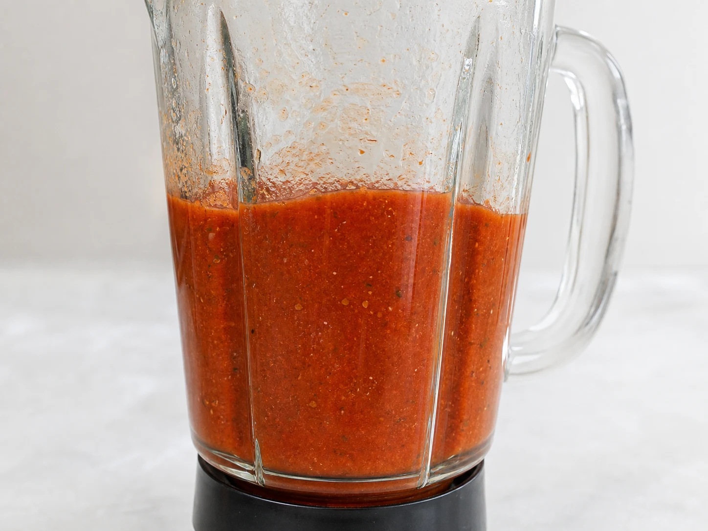 Molho vermelho-tijolo de tomate e chipotle quase liso, com leve textura natural, no copo do liquidificador