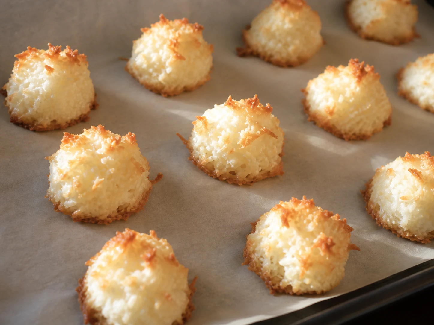Baked coconut cocadas with golden tips and one visible golden base on the baking sheet