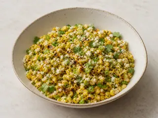 Tazón de ensalada de elote estilo callejero con Cotija, cilantro, limón y maíz tostado