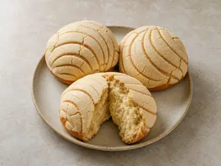 Conchas mexicanas de vainilla con costras claras de azúcar marcadas, sobre un plato de cerámica