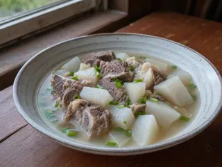 Bowl of clear lamb and daikon soup finished with scallions and cilantro