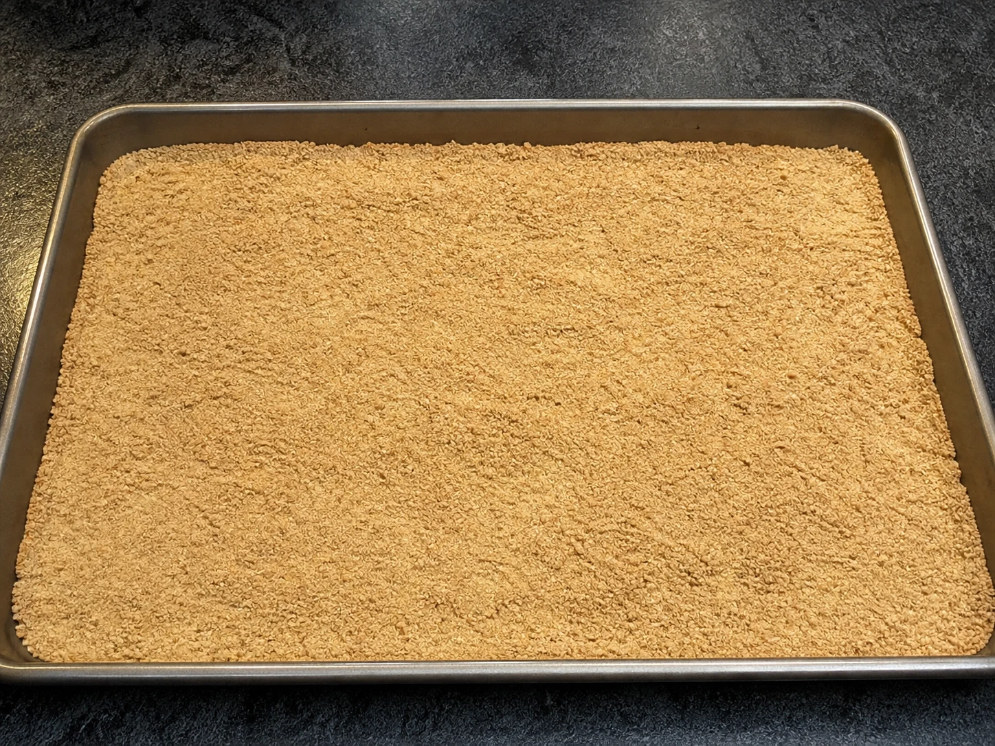Evenly toasted commercially heat-treated all-purpose flour, warm beige and lump-free, on a rimmed baking sheet