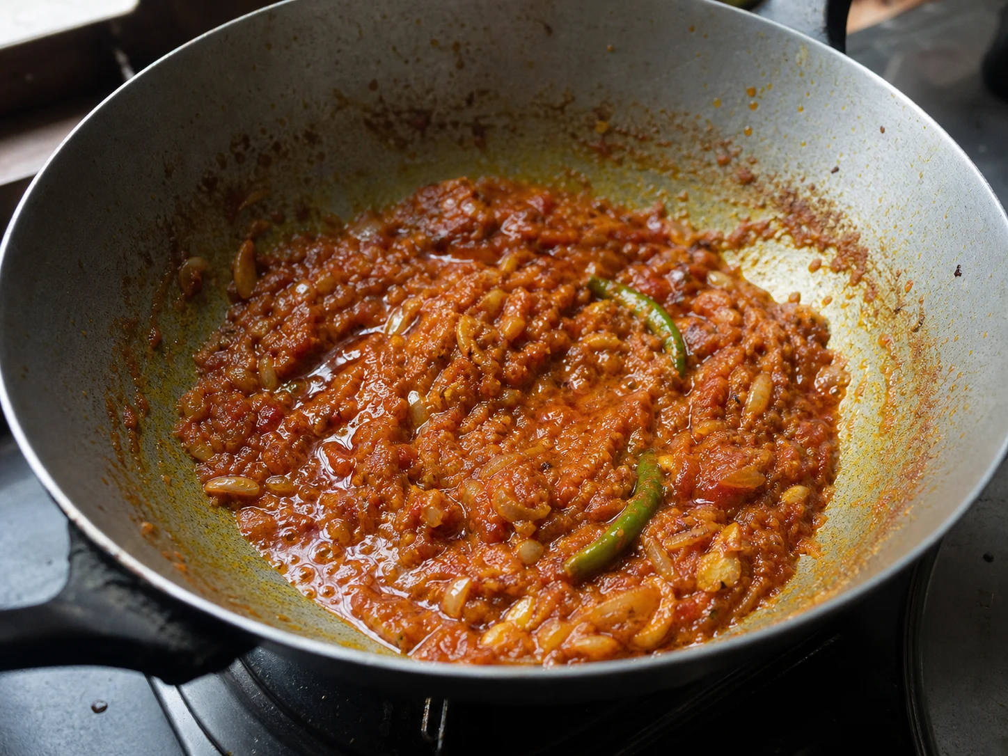 Base espessa de tomate e cebola cor de ferrugem, com pequenas gotas de óleo nas bordas