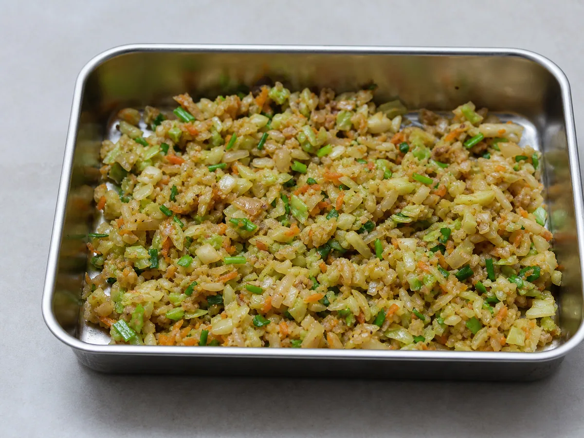 Relleno seco de verduras tiernas y crujientes extendido en un plato para enfriar