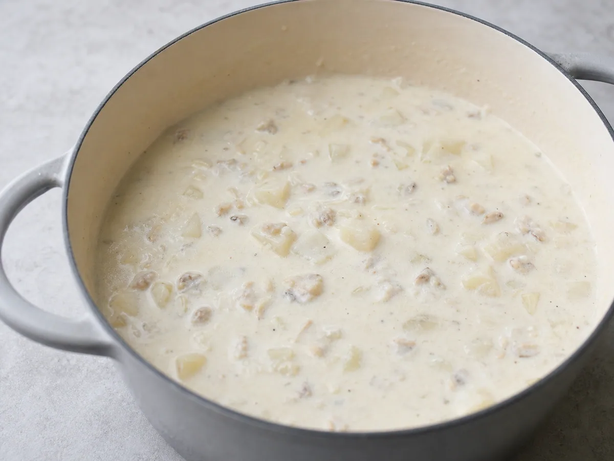 Sopa cremosa de almejas humeante en la olla después de calentar las almejas y el tocino cocido