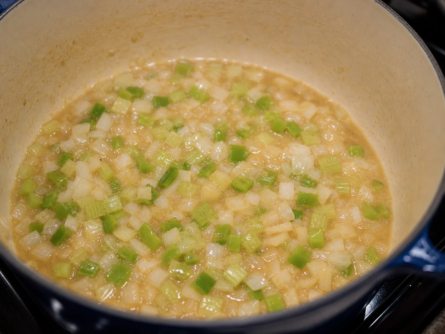 Softened onion, green bell pepper, and celery glossy in the blond roux without browning