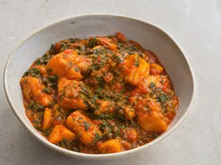 Tazón de guiso nigeriano de ñame con espinaca en salsa de pimiento rojo y aceite de palma