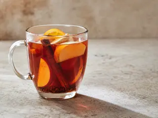 Copos transparentes resistentes ao calor com ponche quente de maçã, canela e rooibos e fatias macias de maçã