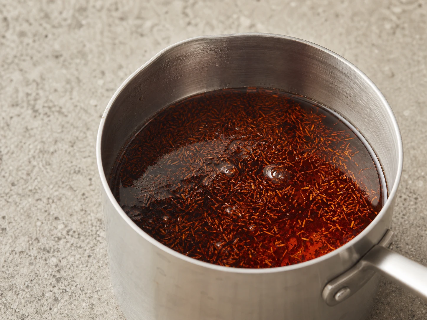 Rooibos vermelho-âmbar intenso em infusão com canela, cravos e gengibre para o ponche de maçã, canela e rooibos