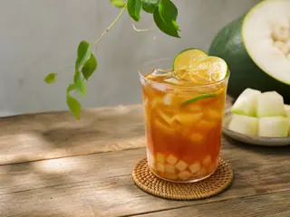 Copo alto de chá gelado âmbar de melão-de-inverno com cubos de gelo transparentes