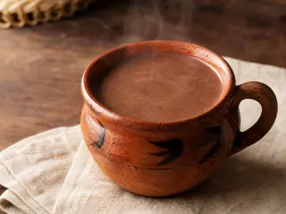 Taza de champurrado mexicano espeso con canela y una capa ligera de espuma