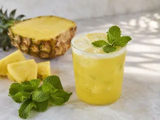 Vasos transparentes de agua fresca de piña y menta con hielo, menta y piña