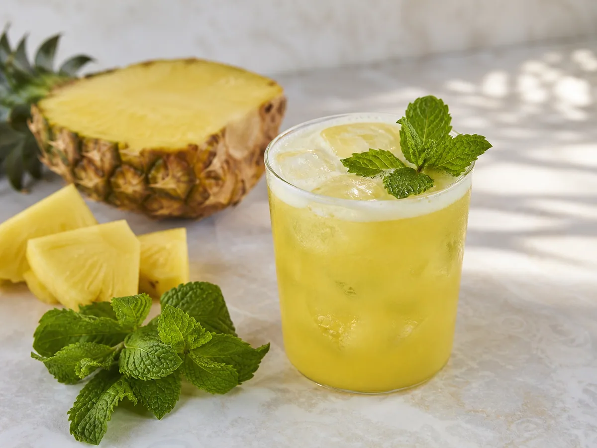Clear glasses of pineapple mint agua fresca with ice, mint, and pineapple