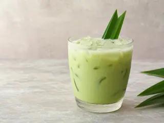 Vaso alto de refresco verde pálido de pean y leche de coco con hielo