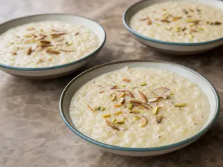 Tazón bajo de barro con kheer pakistaní de arroz con cardamomo, cubierto de almendras y pistachos