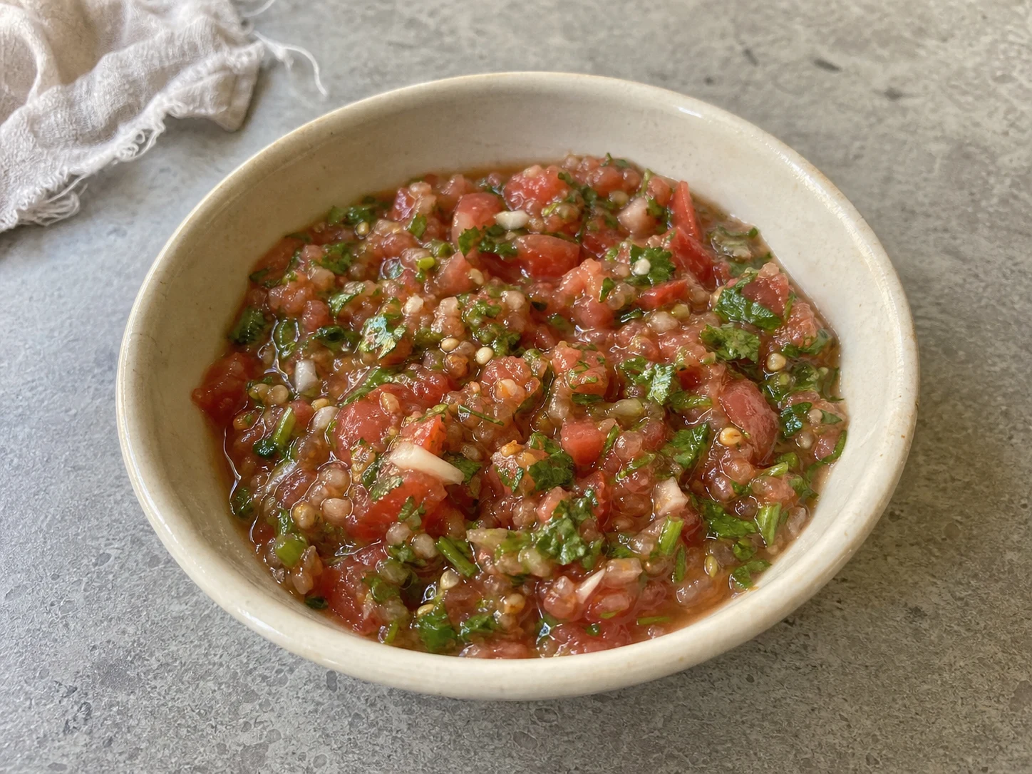 Chutney fresco e rústico de tomate, com pedaços visíveis de coentro, pimenta verde e alho