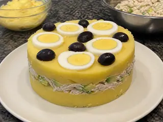 Causa peruana de pollo desmoldada con capas de papa dorada, aguacate y pollo cremoso