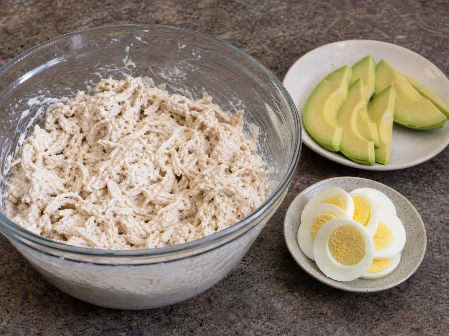 Relleno cremoso de pollo cocido con aguacate rebanado y huevos duros para causa peruana de pollo