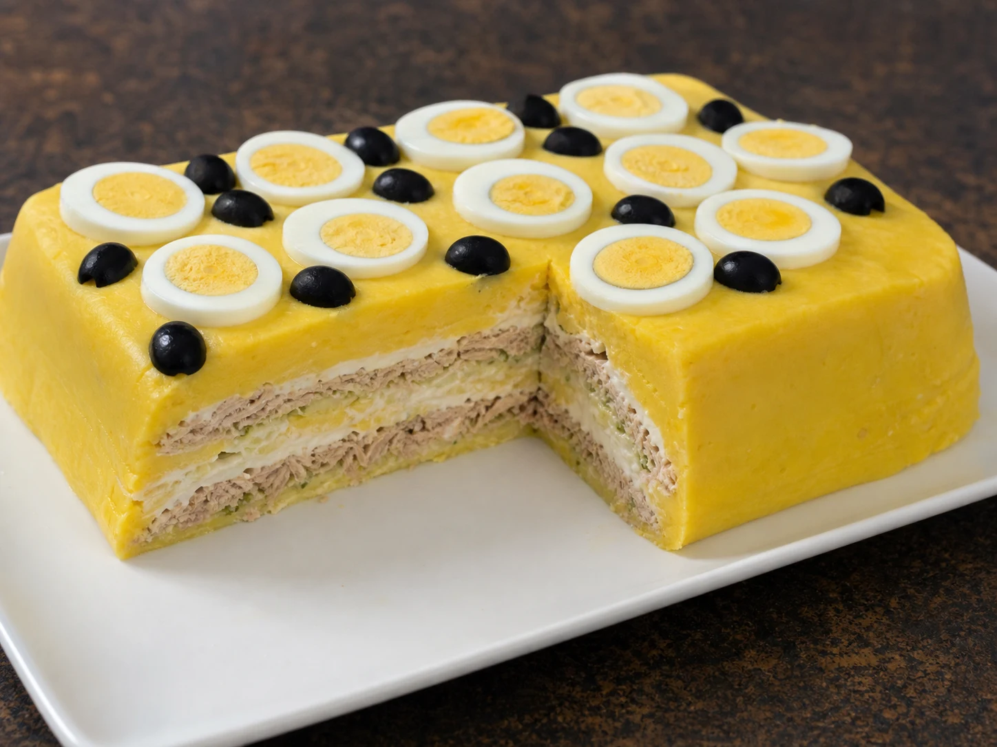 Causa peruana de pollo recién desmoldada, con capas intactas de papa, aguacate y pollo cocido