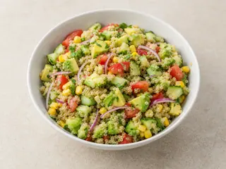 Tazón de ensalada de quinoa con aguacate inspirada en Perú, con maíz tostado y tomates