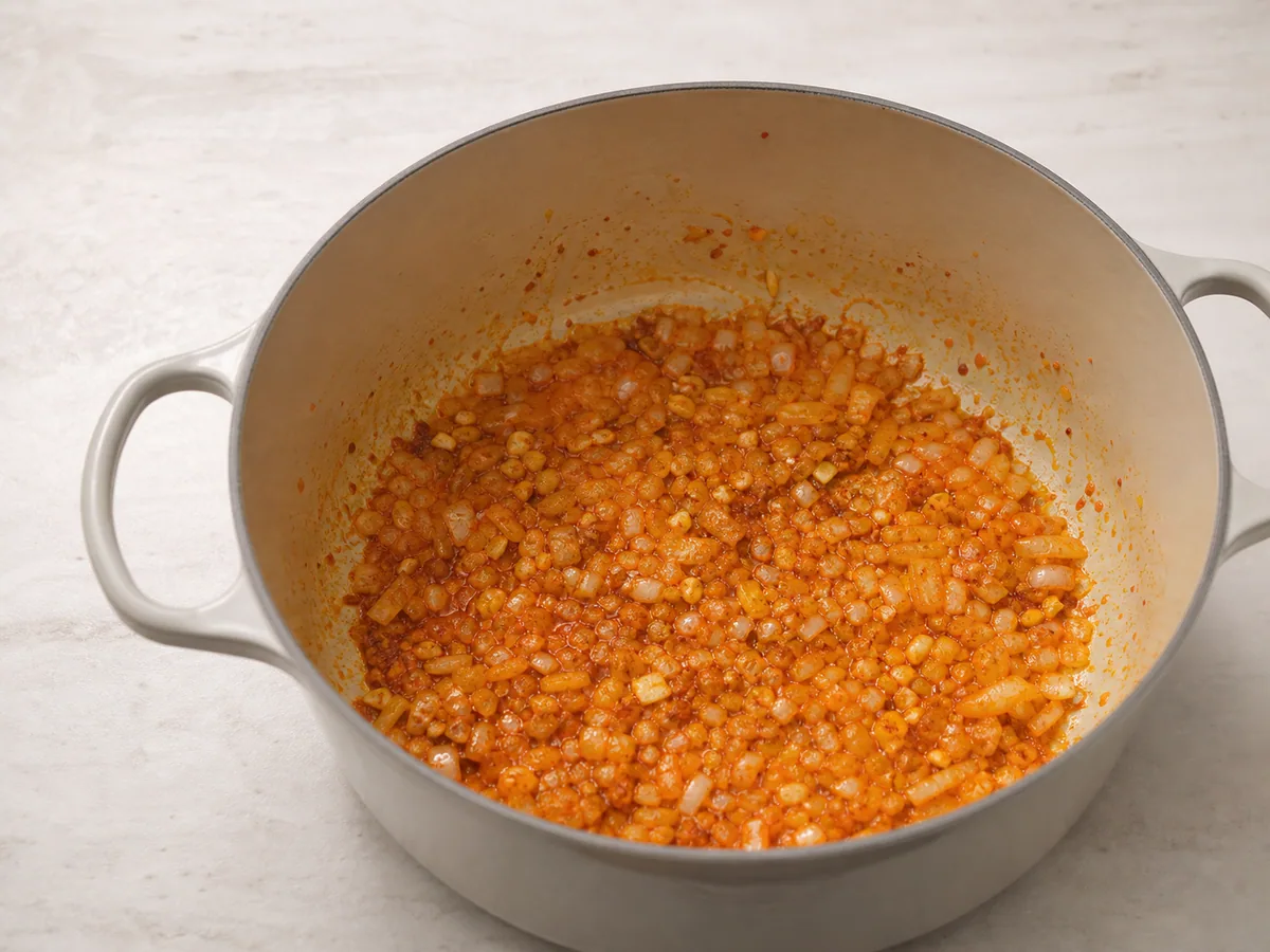 Base de ají para sopa peruana de quinoa, con cebolla suave y pasta de chile oscurecida en una olla
