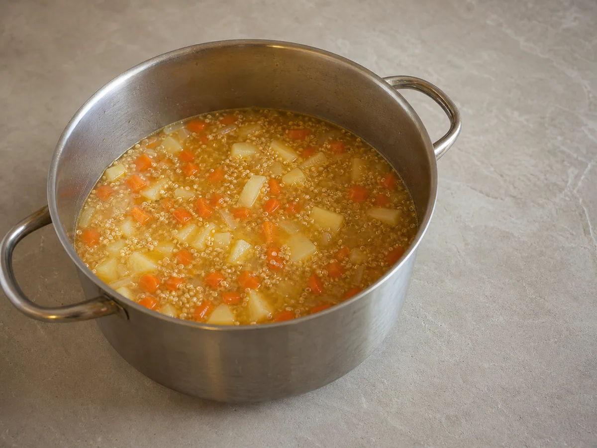 Sopa peruana de quinoa a fuego lento, con espirales de quinoa abiertas y papas casi tiernas