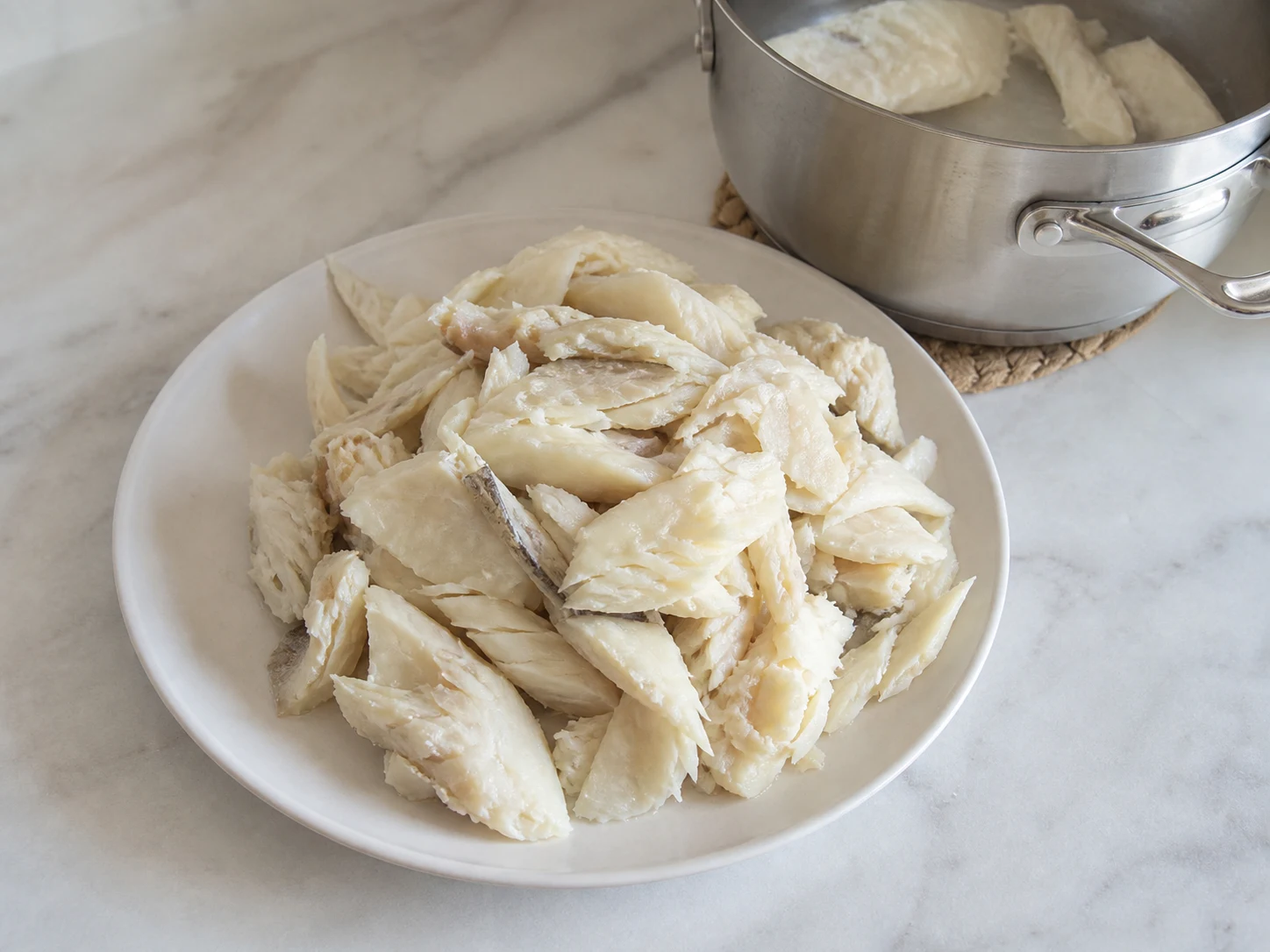 Bacalhau já dessalgado, opaco e bem cozido, separado em lascas largas para o Bacalhau à Brás