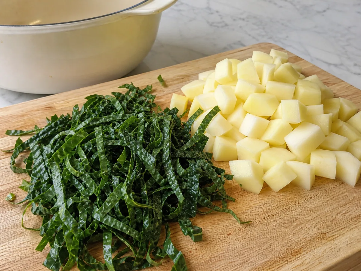 Lacinato kale cut into fine ribbons beside peeled potato pieces for caldo verde