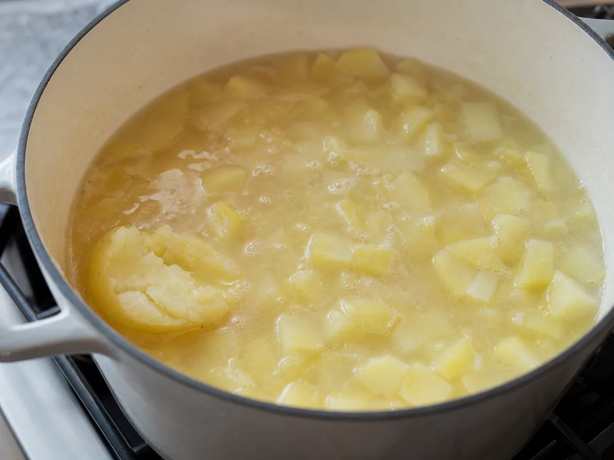 Tender potato pieces crushing easily in the pale broth before blending caldo verde