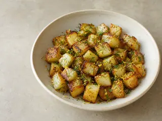 Roasted kohlrabi with browned edges, lemon, and fresh dill in a shallow bowl