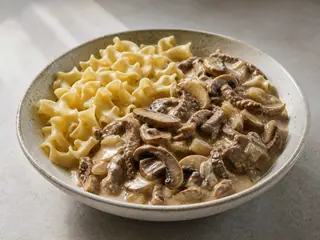 Tazón de stroganoff ruso cremoso de champiñones con fideos de huevo y eneldo fresco