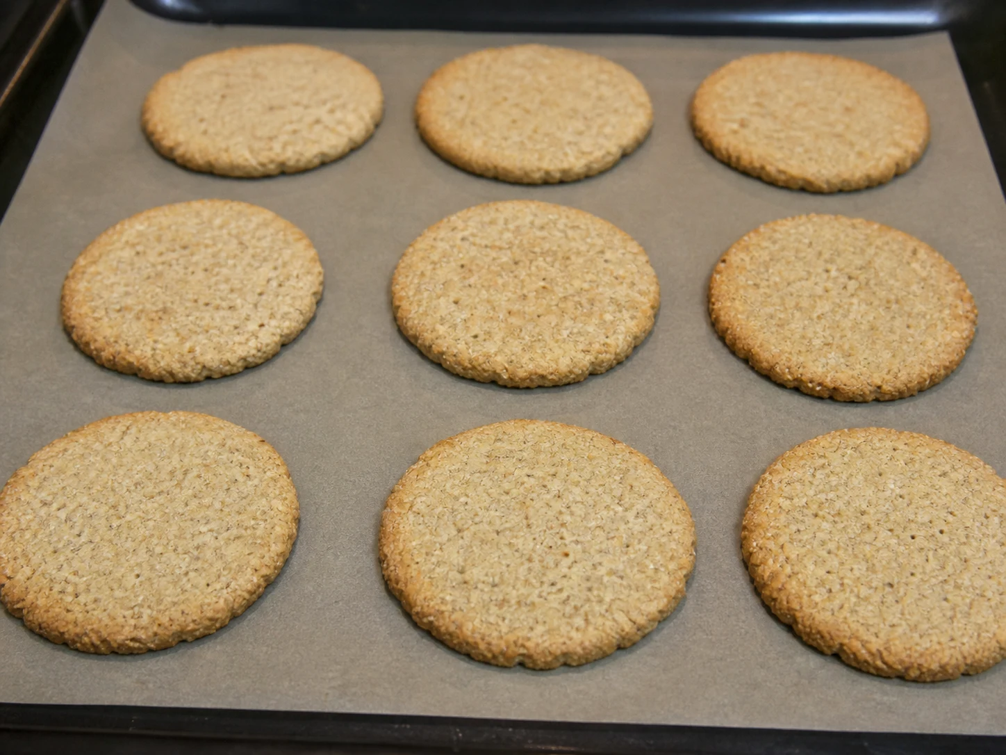 Scottish oatcakes baked dry with lightly golden edges on a parchment-lined tray